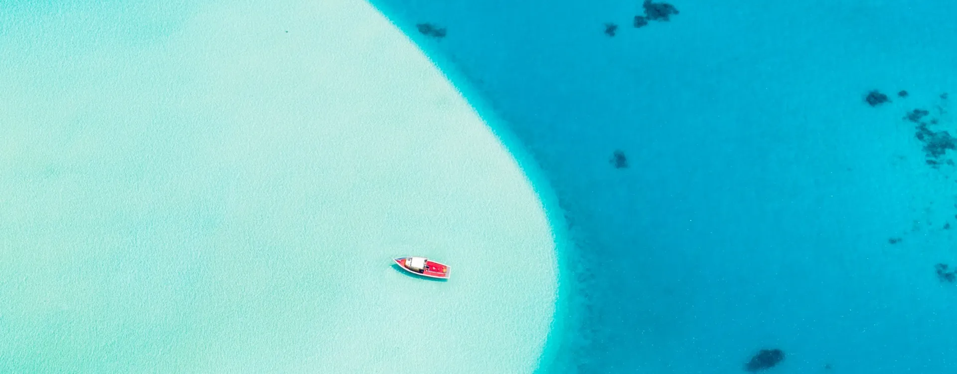 Small red and white boat in the turquoise waters of the Maldives