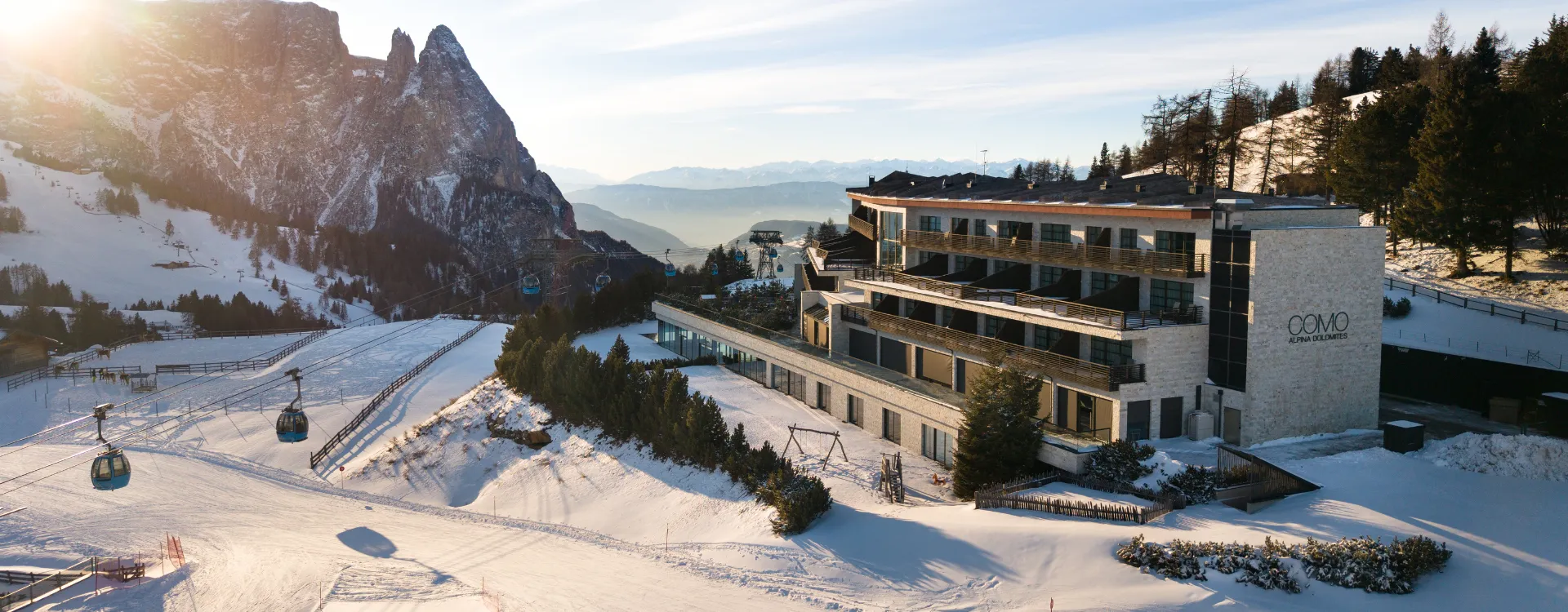 Exterior view of COMO Alpina with the Dolomites in the background.